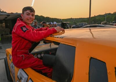 A young man posing by his stock car during race night.