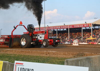 A tractor spits black smoke and rises off of its front wheels.