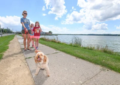 Mother and daughters walking alongside their puppy on a pathway near Lake Tomah.
