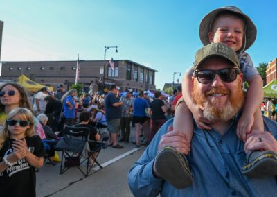 a child sits on his fathers shoulders in a crowd