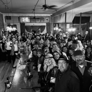 A photo of people dressed in prohibition era clothing at a busy bar