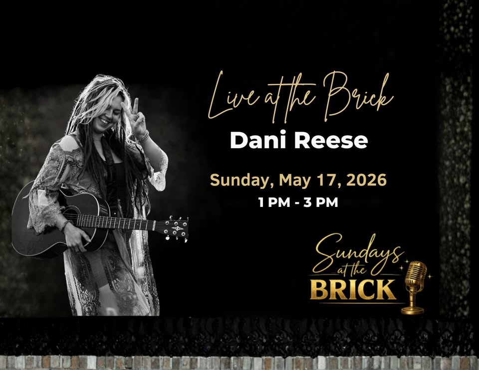 A photo of Dani Reese holding a guitar and the peace sign.