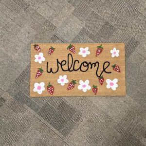A welcome mat painted with flowers and strawberries