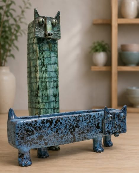 A tall vase and a wide planter both with cat faces.