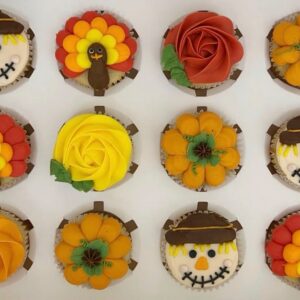 A dozen decorated cupcakes as pumpkins, turkeys, etc.
