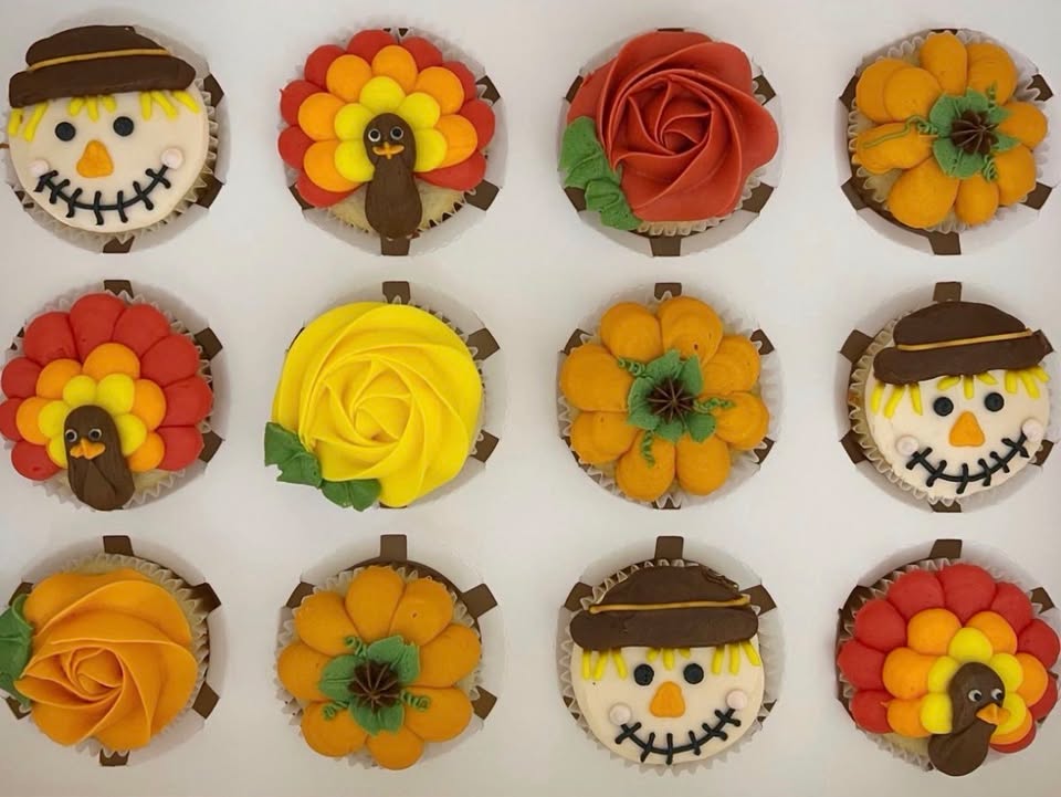 A dozen decorated cupcakes as pumpkins, turkeys, etc.