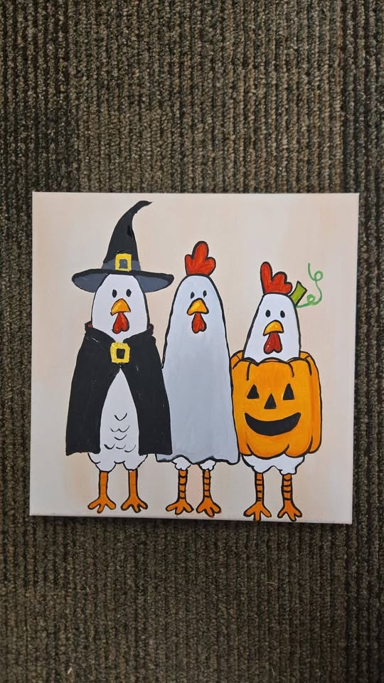 A canvas painting of three chickens in Halloween costumes