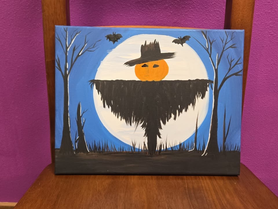 A canvas painting of a scarecrow in front of the full moon.