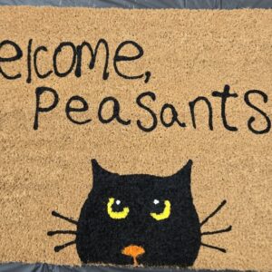 a doormat with the words "welcome peasants" above a black cat